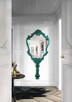 an ornate green mirror in the corner of a room with white walls and wood floors