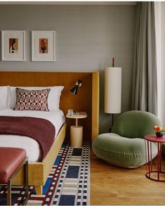 a bed sitting in a bedroom next to a chair and table on top of a hard wood floor