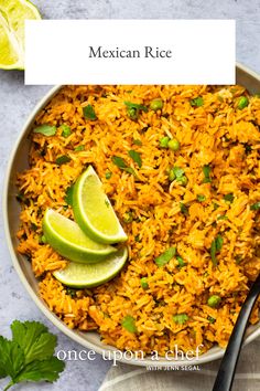 mexican rice in a bowl with lime wedges and cilantro on the side