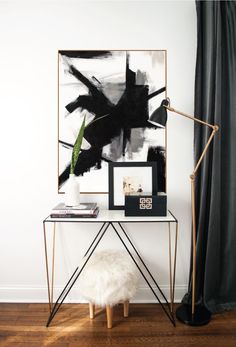 a black and white painting sitting on top of a wooden floor next to a table