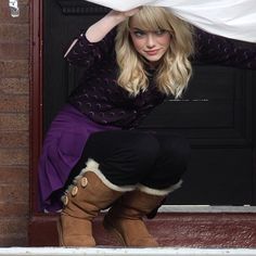 a woman sitting on top of a door with her hands over her head and wearing boots