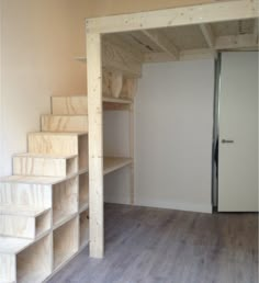 an empty room with some shelves and stairs in the corner, next to a door