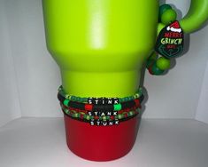 a stack of bracelets sitting on top of a green cup with the word grinch written on it