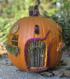 a pumpkin with a house built into it's side sitting on the ground in front of some plants