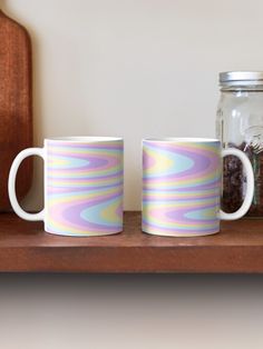 two coffee mugs sitting on top of a wooden shelf