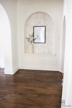 an empty room with white walls and wood flooring is seen in this image from the doorway