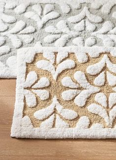 two rugs on the floor with white and beige designs