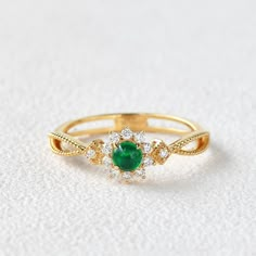 an emerald and diamond ring on a white surface