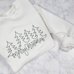 **Due to supply shortages, we may have to use a different brand blank. So colors may vary slightly with heathered grey. Quality and fit will be the same.**  This super soft crewneck sweatshirt is made with a super soft and quality blank and each shirt is embroidered printed. Shirts are made with love and care and made to order. Snag yours now for a unique fashion statement. Color Options For Crewneck: Black  Crewneck (White Embroidery) White Crewneck (Forest Green Embroidery) Grey Crewneck (Fore Christmas Embroidered Sweatshirt, Green Embroidery, Merry Christmas Tree, White Crewneck, Embroidery Sweatshirt, Grey Crewneck, Embroidered Crewneck, Black Crewneck, Pink Crewneck