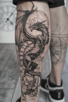 a man's leg with a dragon and compass tattoo on the side of his leg