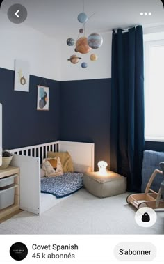 a child's bedroom decorated in blue and white with planets hanging from the ceiling