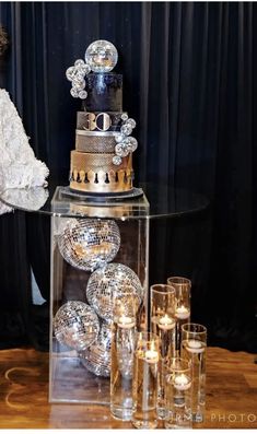 a table topped with a cake covered in lots of shiny silver decorations next to candles