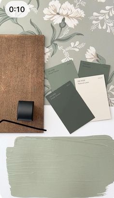 some paint swatches are sitting on a table next to a wooden frame and wallpaper