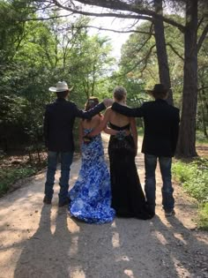 four people standing in the middle of a dirt road with their backs to each other