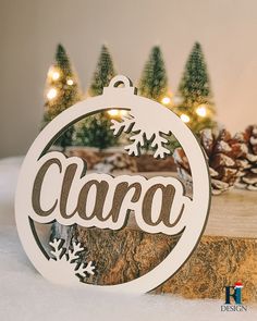 a christmas ornament with the word clara on it and snowflakes in the background