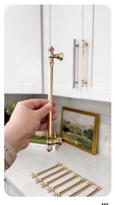 a person is holding a golden door handle on a white counter top with gold hardware