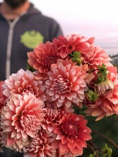 a man standing next to a bunch of pink flowers