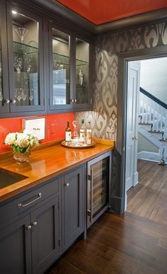 a kitchen with wooden counter tops and gray cupboards next to a stair case that leads up to the second floor