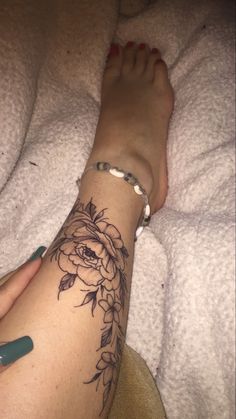 a woman's foot with a flower tattoo on her left arm and right leg