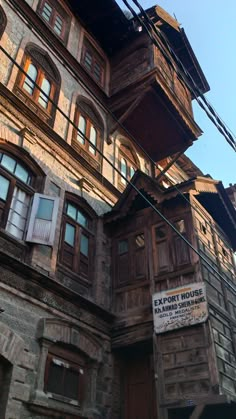 an old building with wooden windows and balconies on the top floor, next to a street sign