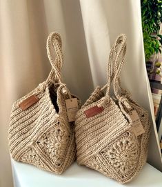 two crocheted bags sitting on top of a white shelf