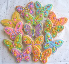 decorated cookies are arranged in the shape of butterfly's on a white tablecloth