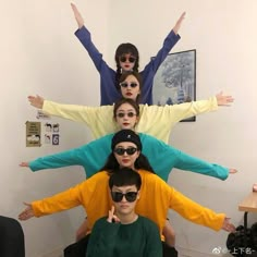 four people with their arms in the air and one person wearing sunglasses on his head