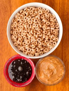 two bowls filled with peanut butter and pretzels next to each other on a wooden table