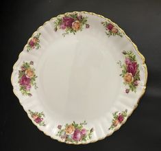 a white plate with pink and yellow flowers on it sitting on a black table top