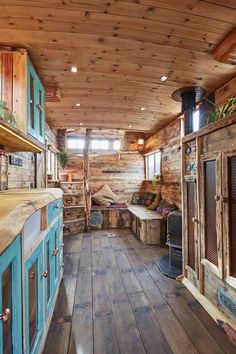 the inside of a cabin with wood floors and blue cupboards on either side of the stove