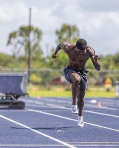 a man running on a race track in the middle of his body and one leg up