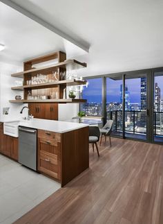 a kitchen with wooden cabinets and white counter tops next to a large window overlooking the city