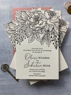 wedding stationery with flowers on it and a key laying next to the stationery