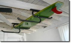 a green surfboard hanging from the ceiling in a room with white walls and curtains