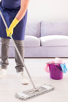 a man in blue apron cleaning the floor with a mop