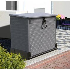 a gray storage box sitting on top of a brick walkway