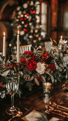 a table topped with candles and flowers next to a christmas tree