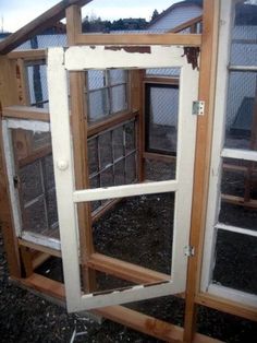 an open window on the side of a building with wood frame and glass panels in it