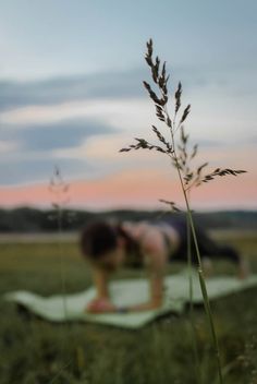 a woman doing yoga in the middle of a field with grass and sky behind her