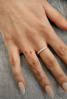 a woman's hand with a small star tattoo on her left ring and the other finger