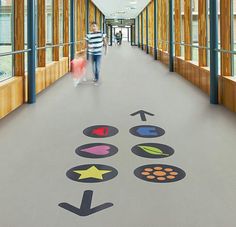 two people walking down a long hallway with arrows painted on the floor and an arrow pointing towards each other