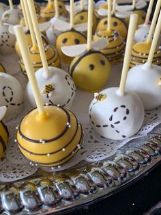 cake pops with yellow and white decorations on a silver platter