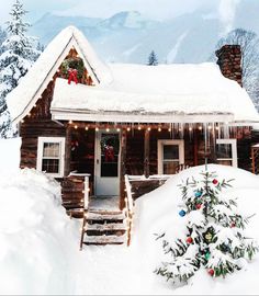 a log cabin with christmas lights on the roof and stairs leading up to the front door