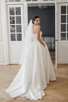 a woman in a white wedding dress standing on a wooden floor