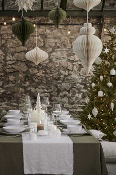 a dining room table set for christmas dinner with paper lanterns hanging from the ceiling and decorations on the wall