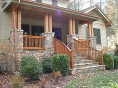 a house with stone steps and wood railings on the front porch, surrounded by trees