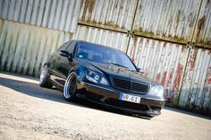 a black car parked in front of a rusty building