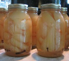 four jars filled with pickles sitting on top of a table