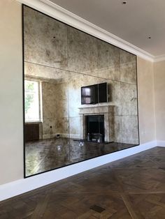 an empty room with a large mirror on the wall and a fireplace in the corner