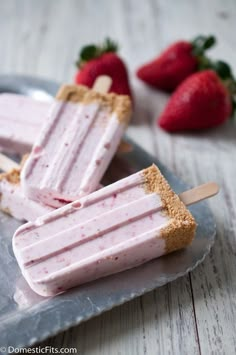 strawberry ice cream popsicles on a blue plate with strawberries in the back ground